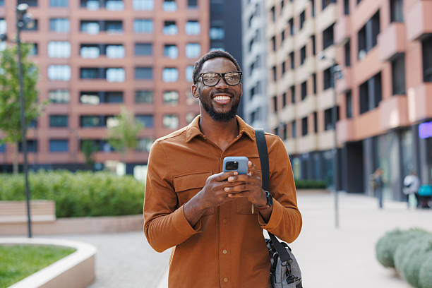 istock Smiling man holding his smartphone outdoors in a modern urban setting 2211257248