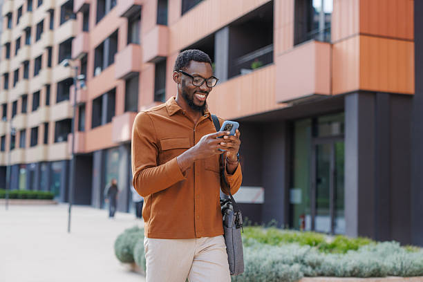 istock Smiling man using smartphone outdoors near a modern building 2211257254