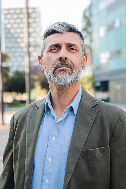 istock Vertical. Confident mature businessman looking at camera with a serious expression, professional man with beard in a suit jacket standing outdoors, exuding leadership and experience 2211258728