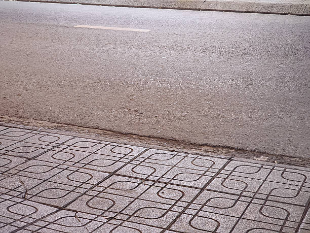 Asphalt road borders a decorative patterned sidewalk in a clean, urban street environment.