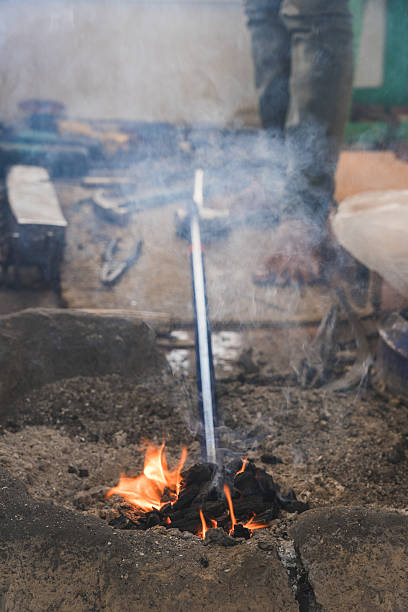 Metal worker heating iron rod in burning coals in a traditional forge in oman