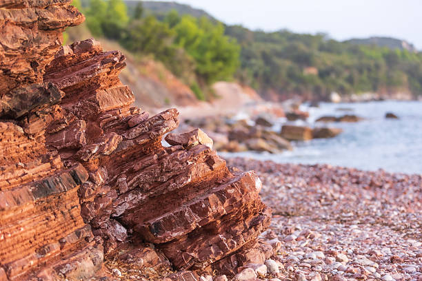 Wild beach Crvena Glavica in Montenegro. Red rocks coast and water waves
