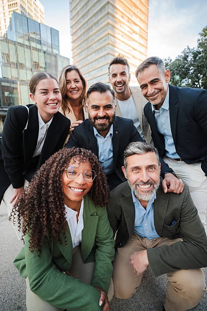 istock Vertical. Diverse group of business professionals smiling and looking at the camera during an outdoor meeting, showcasing teamwork. Successful businesspeople looking at camera together at the downtown 2211261430
