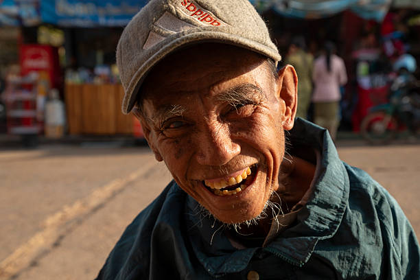Pakse, Laos - Dec 5, 2019: An older man, of advanced age, explains to me his work as a sharpener smiling, in the Bai Don market in Pakse
