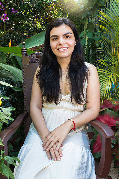 A young woman is sitting smiling and looking at the camera