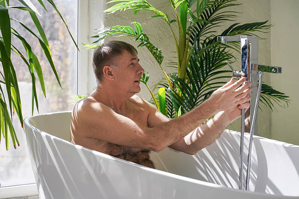istock Man taking bath in modern bathroom.  Take bath, relaxing at home, body care concept. Man having bath, sitting in bathtub 2211264592