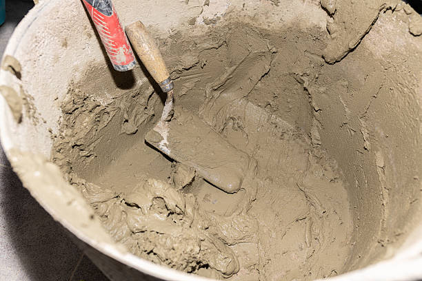 istock Metal trowel mixing cement in bucket preparing for construction works 2211265747