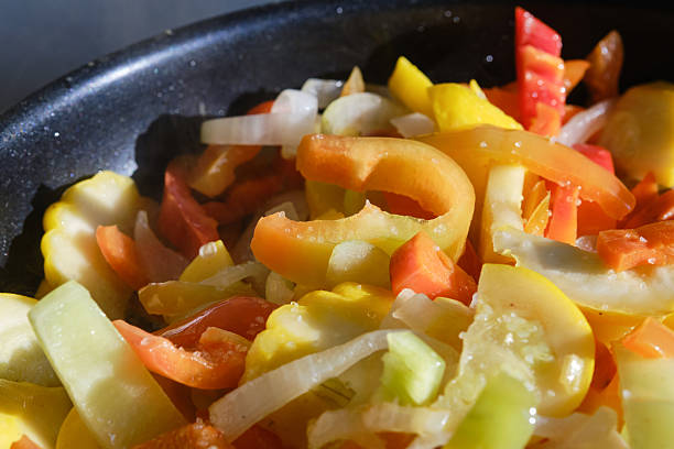 Fresh raw fried vegetables in a frying pan, close up. Shallow depth of field
