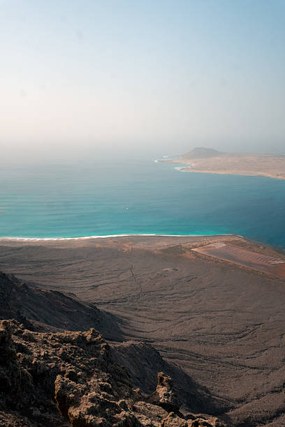 Elevated view of calm bay and arid hills in rugged volcanic landscape, Lanzarote Island, Canary Islands