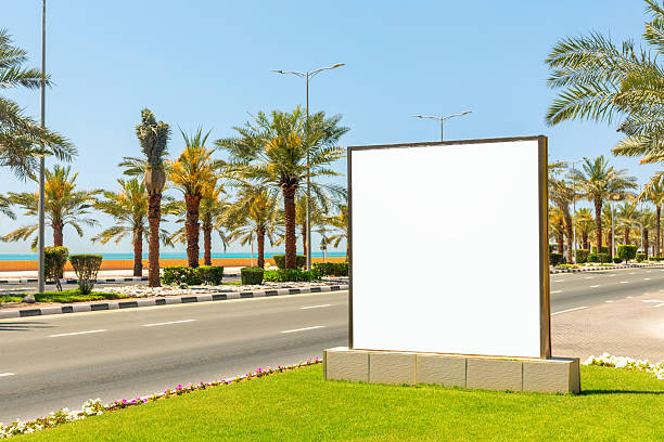 istock mockup billboard on empty road  with blue sky and palm trees in a sunny day 2211270810
