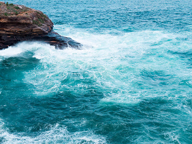 Vibrant turquoise ocean waves crashing against rocky coastline.