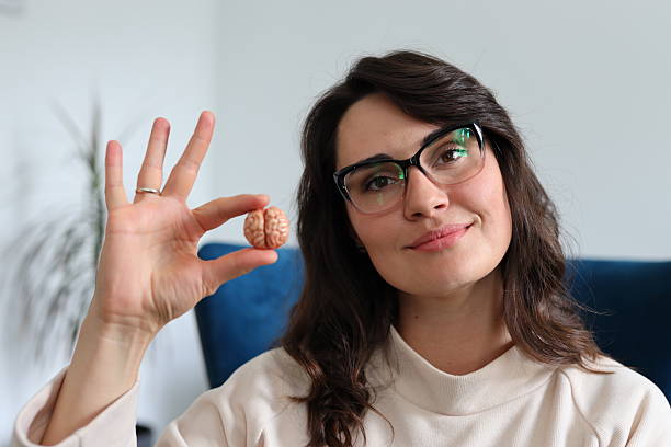 A woman is holding two small round objects in her hand, one of which is labeled 