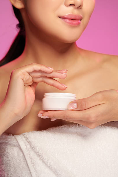 istock Skincare routine featuring a woman applying cream with a soft focus background in a serene setting 2211273542