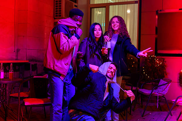 Friends enjoying a lively evening gathering outdoors in a vibrant setting with colorful lights during autumn