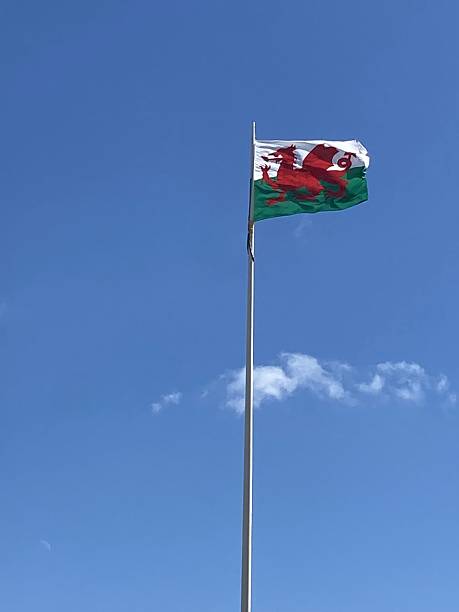 istock Blue sky with a white wisp of cloud featuring the Wales national flag on a flagpole. 2211275393