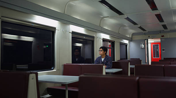 A man solo traveler is sitting alone on a train and travelling at night