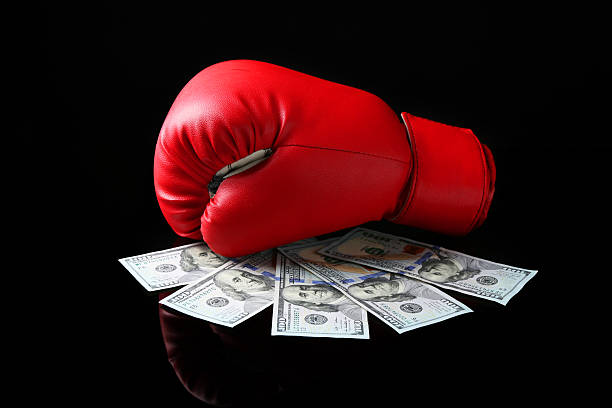 istock Red boxing glove and dollar banknotes on black mirror surface 2211279051