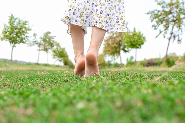 Woman walking barefoot on green grass outdoors, closeup