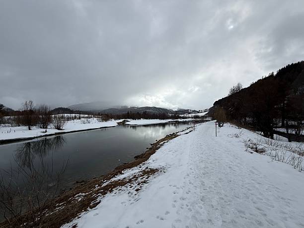 istock Serene winter landscape with snowy path and river. 2211279167