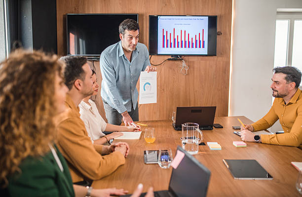 istock Businessman explaining graph to a small group of his colleagues in board room 2211279523