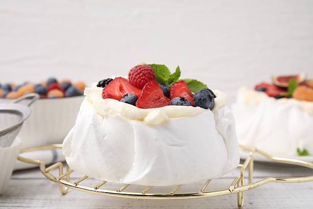 istock Pavlova cake (meringue dessert) with whipped cream, fresh berries and mint on table, closeup 2211280113