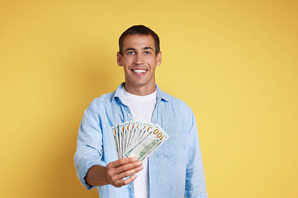 istock Happy man with money on yellow background 2211281915