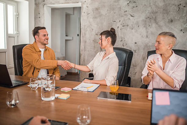istock Two carefree business colleagues sitting at a conference table and shaking hands during a meeting with colleagues in a conference room, after a successful cooperation agreement 2211282207