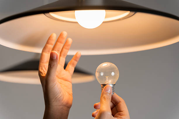 istock Changing Light Bulb. Man installs light fixture in new home. A man changes a light bulb in an apartment. 2211287222