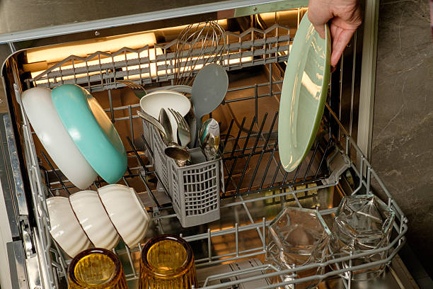 istock Organizing clean dishes in a modern kitchen appliance after dinner preparation 2211288074
