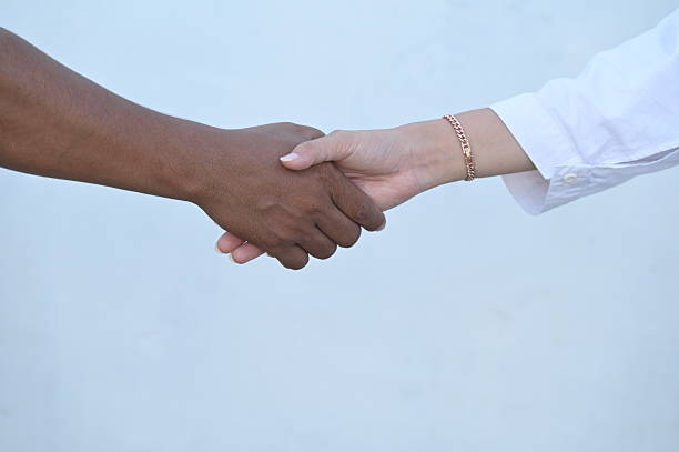 istock White friend shaking hands with black friend 2211288875