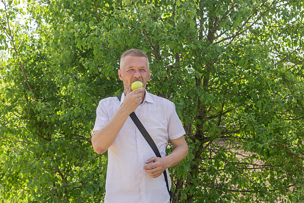 Man eats apple while walking in springtime nature. Healthy lifestyle