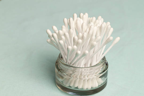 glass jar with cotton swabs, light blue background