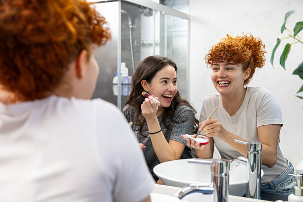 istock Friends putting on make-up together in bathroom mirror 2211290850