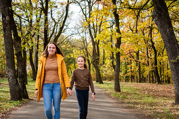istock Mother and daughter walking in park holding hands 2211293899