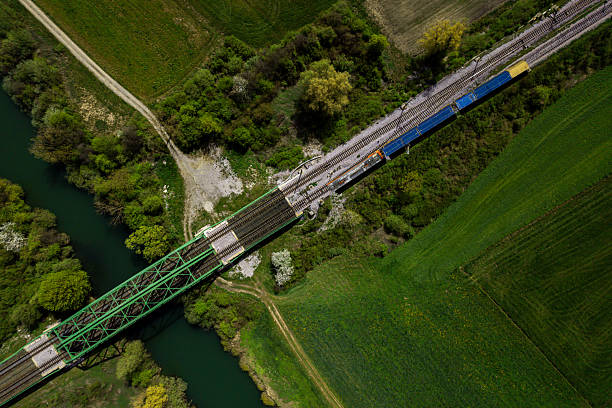 istock Freight train crossing green bridge over river in countryside 2211296966
