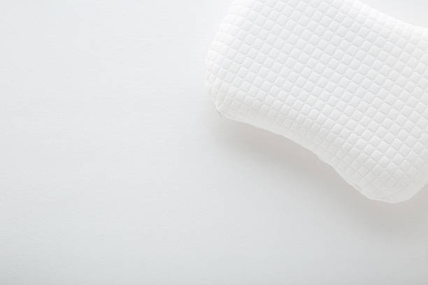 istock White soft memory foam pillow on mattress cloth background. Closeup. Empty place for text. Top down view. 2211297926