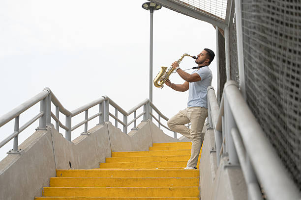 istock Young saxophonist playing on yellow staircase seeking inspiration 2211299639