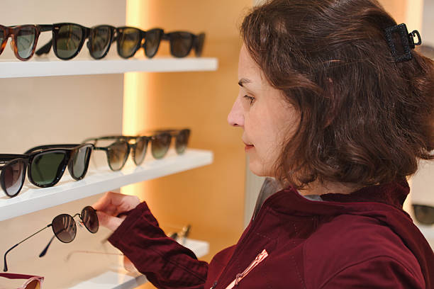Young woman picking sunglasses in the optics store.