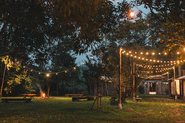 istock Cozy outdoor campfire surrounded by rustic wooden benches and glowing string lights, creating a peaceful evening atmosphere perfect for glamping under the stars in a nature-inspired forest retreat 2211313919