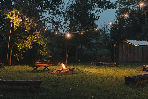istock Cozy outdoor campfire surrounded by rustic wooden benches and glowing string lights, creating a peaceful evening atmosphere perfect for glamping under the stars in a nature-inspired forest retreat 2211313925