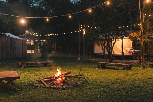 istock Cozy outdoor campfire surrounded by rustic wooden benches and glowing string lights, creating a peaceful evening atmosphere perfect for glamping under the stars in a nature-inspired forest retreat 2211313926