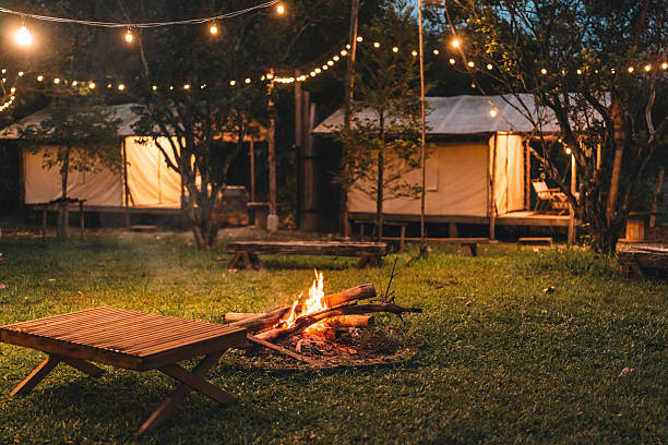 istock Cozy outdoor campfire surrounded by rustic wooden benches and glowing string lights, creating a peaceful evening atmosphere perfect for glamping under the stars in a nature-inspired forest retreat 2211313929