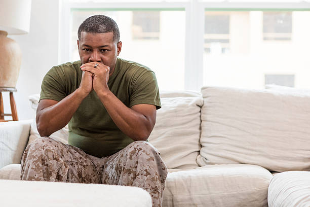 istock Serious African-American Man in Military Uniform Sitting on Sofa 2211314257