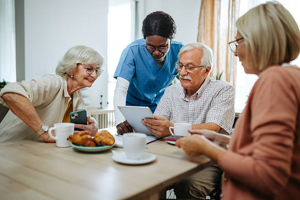 istock Female nurse using digital tablet elderly residents at nursing home 2211318250