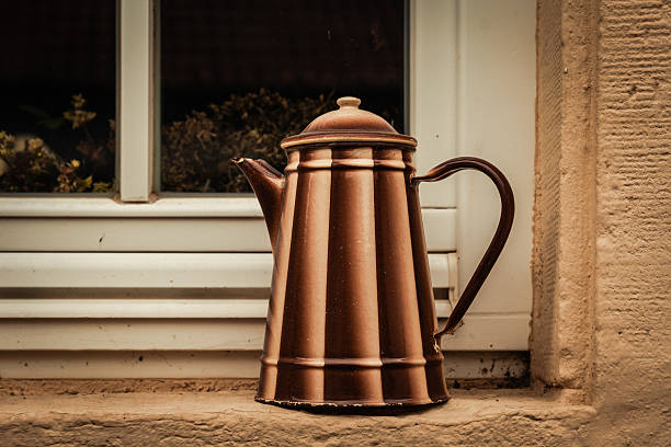 Rustic metal kettle resting on a sunlit window sill in a charming countryside cottage setting