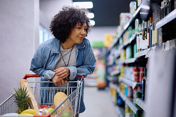 istock Mature shopper looking at wine prices in a supermarket. 2211334621