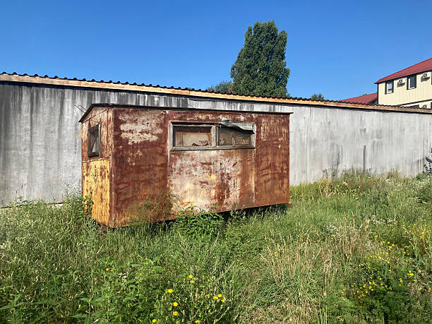 istock An abandoned corrugated metal building on grassy ground with weeds, possibly undergoing disassembly Sky is clear blue, suggesting fair weather 2211342595