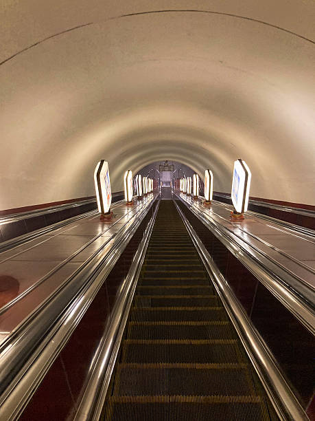 istock Indoor scene with stationary escalators under a red-hued arched ceiling, in a quiet public transit hub 2211342735