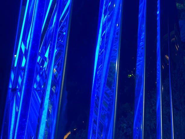 Image of a blue, abstract, futuristic structure with symmetrical design and curved lines, possibly modern art or architecture Taken at night or in low light conditions, with reflections suggesting w