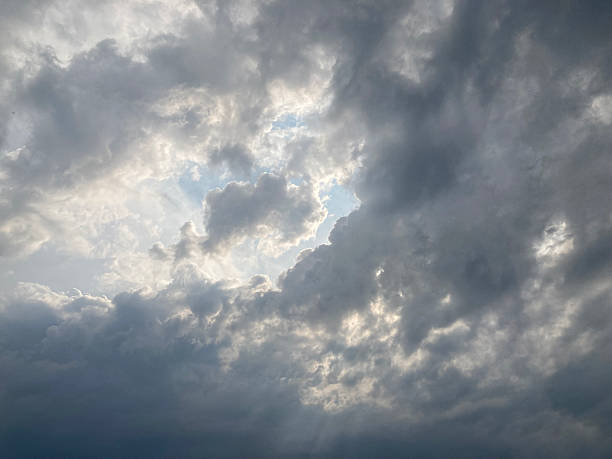 istock Dramatic sky filled with dense, textured clouds, covering frame Sunlight filters through breaks, creating contrast and golden light beams Artificial image alteration suggests digital editing or cro 2211343199